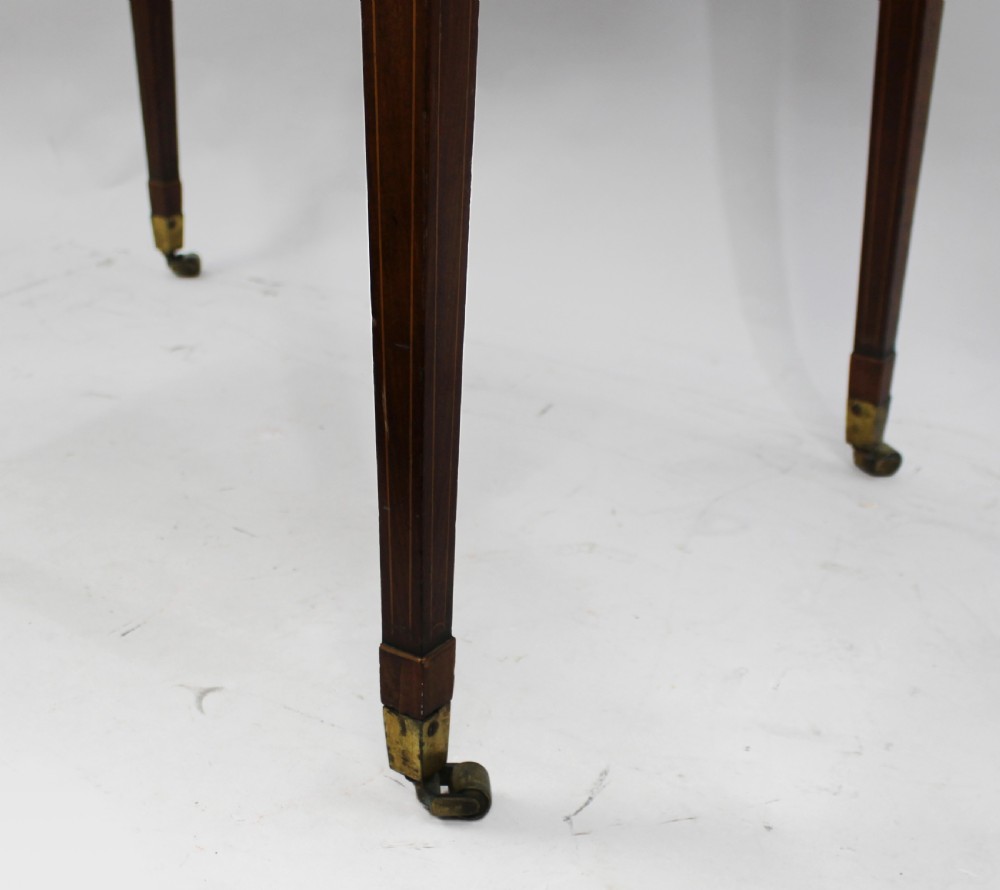 A George III mahogany Pembroke table featuring two hinged drop leaves, crossbanded inlay work, a single drawer with a brass ring handle, and square tapered legs with brass castors. View VI