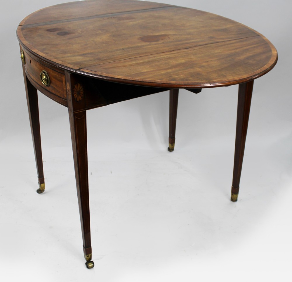 A George III mahogany Pembroke table featuring two hinged drop leaves, crossbanded inlay work, a single drawer with a brass ring handle, and square tapered legs with brass castors. View VII