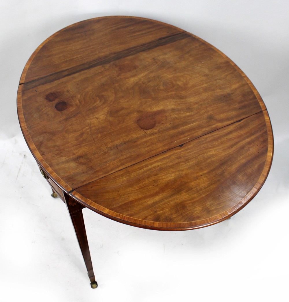 A George III mahogany Pembroke table featuring two hinged drop leaves, crossbanded inlay work, a single drawer with a brass ring handle, and square tapered legs with brass castors. View VIII