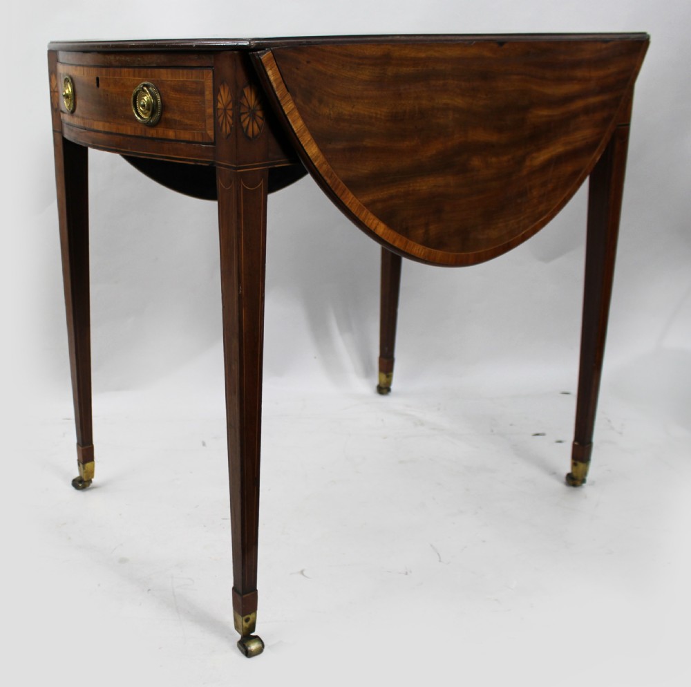 A George III mahogany Pembroke table featuring two hinged drop leaves, crossbanded inlay work, a single drawer with a brass ring handle, and square tapered legs with brass castors. View IX