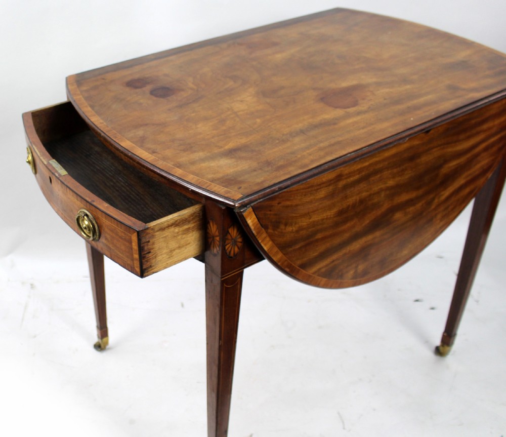 A George III mahogany Pembroke table featuring two hinged drop leaves, crossbanded inlay work, a single drawer with a brass ring handle, and square tapered legs with brass castors. View X