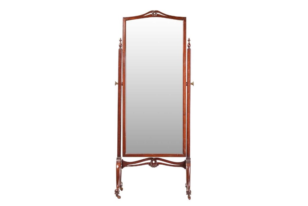 An Edwardian mahogany full-length cheval mirror featuring an arched cresting, swivelling frame, side uprights with finials, and splayed legs on brass castors.