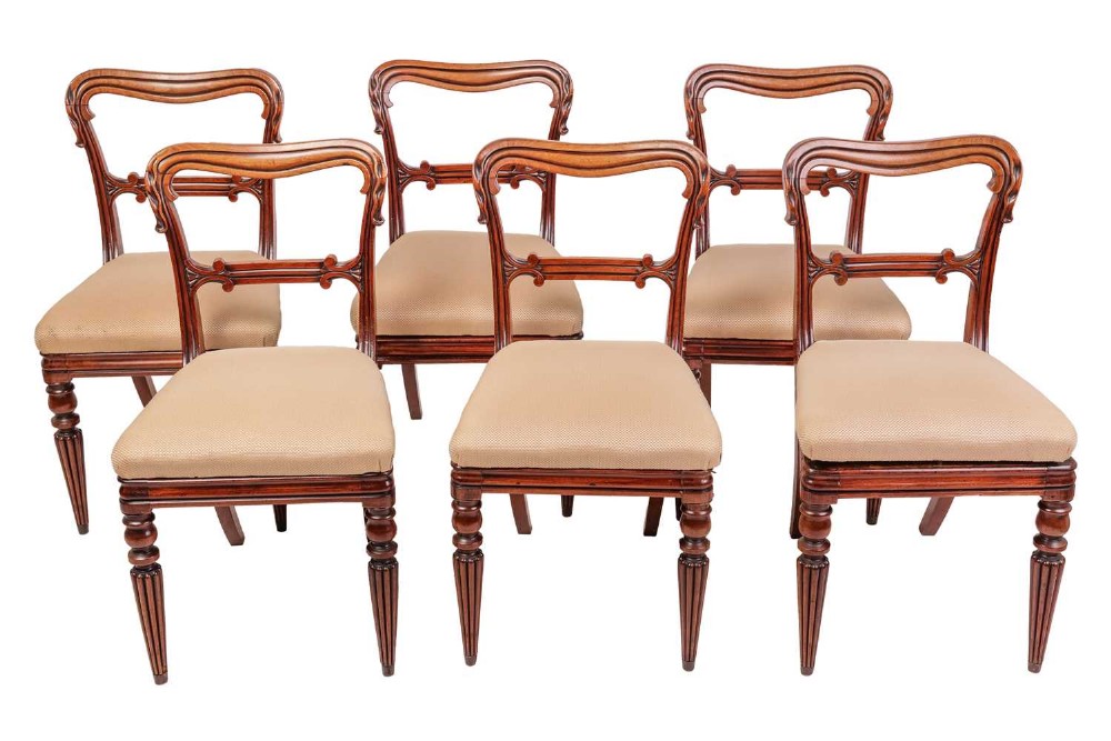 Set of six William IV mahogany dining chairs with carved balloon backs, beige upholstered seats, and fluted turned front legs.