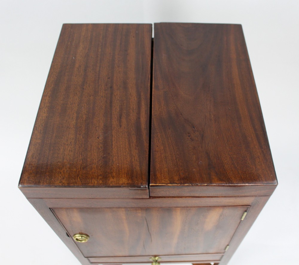 A George III mahogany vanity stand featuring a split folding top, a single cupboard door with a brass ring handle, a drawer, and an X-frame lower stretcher. View IV
