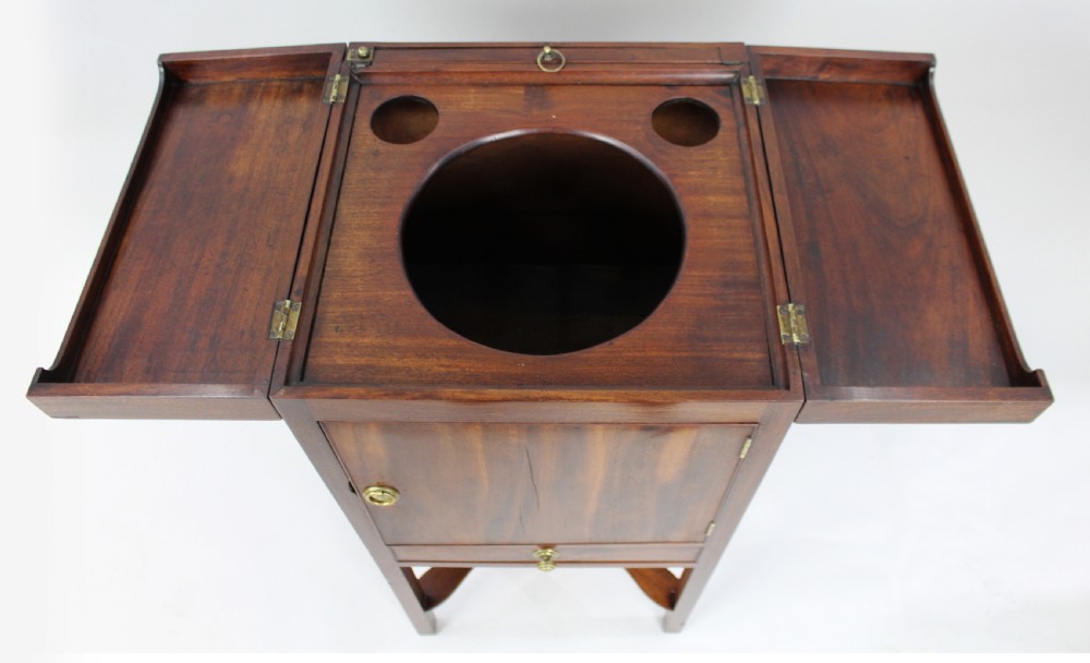 A George III mahogany vanity stand featuring a split folding top, a single cupboard door with a brass ring handle, a drawer, and an X-frame lower stretcher. View V