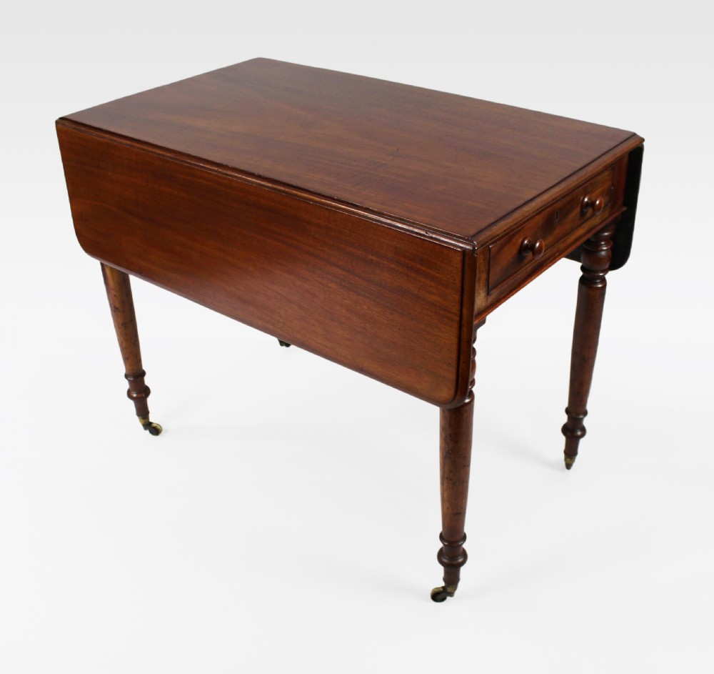 A Regency period mahogany Pembroke table featuring two drop leaves, a single end drawer with wooden turnings, four turned legs, and brass castors.