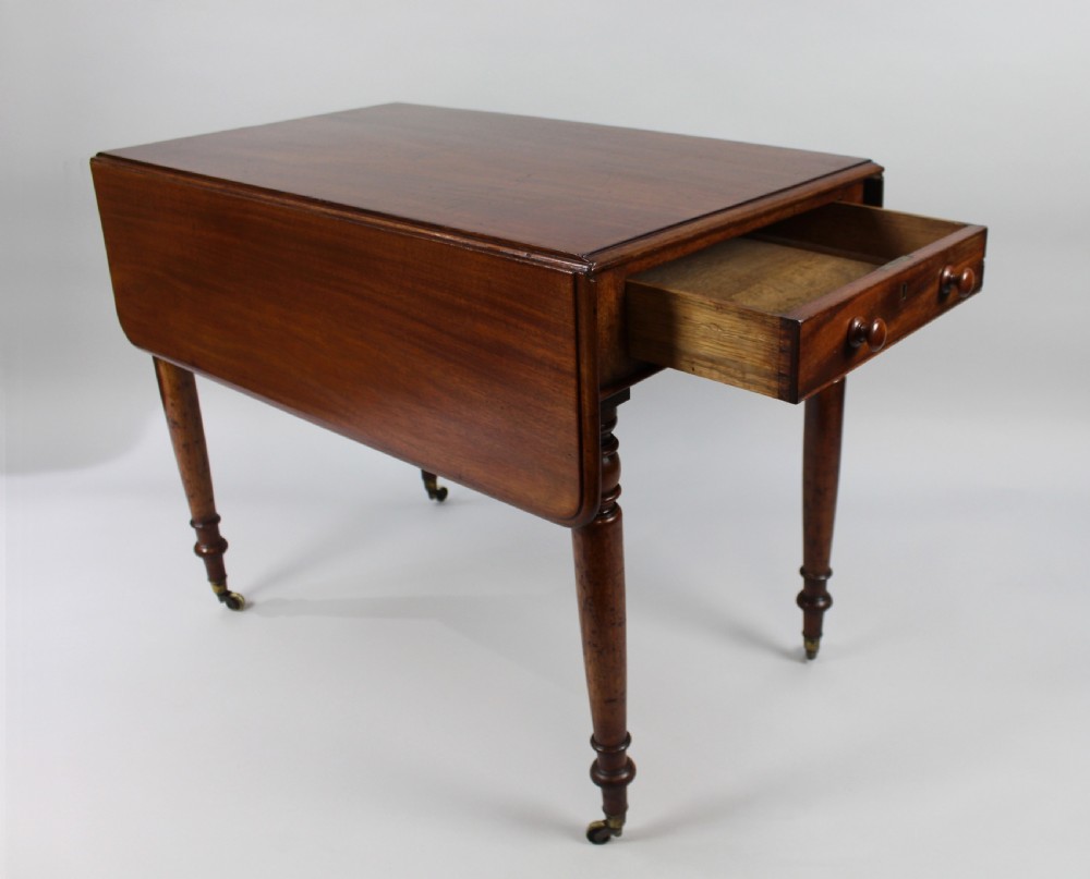 A Regency period mahogany Pembroke table featuring two drop leaves, a single end drawer with wooden turnings, four turned legs, and brass castors. View IV
