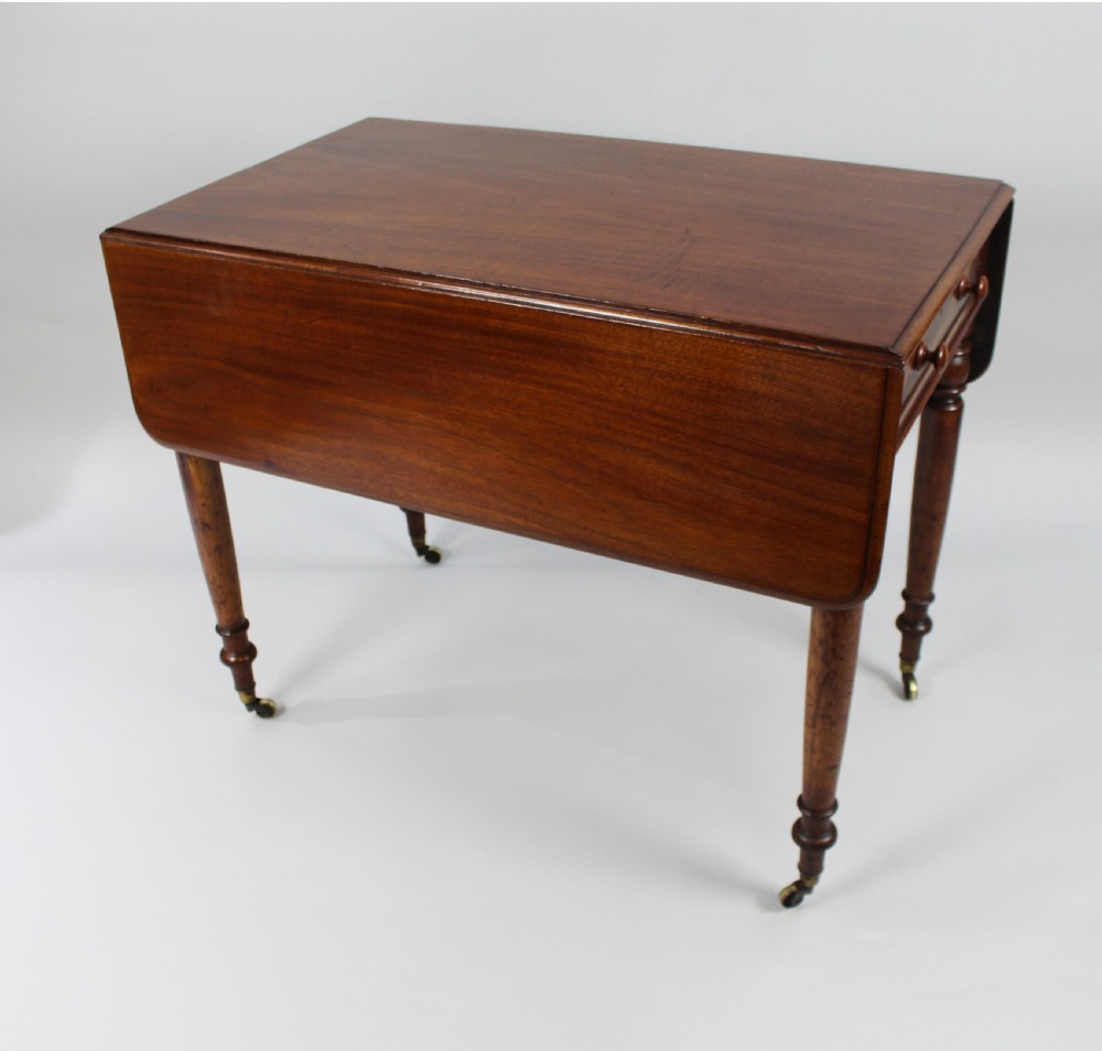 A Regency period mahogany Pembroke table featuring two drop leaves, a single end drawer with wooden turnings, four turned legs, and brass castors. View VI