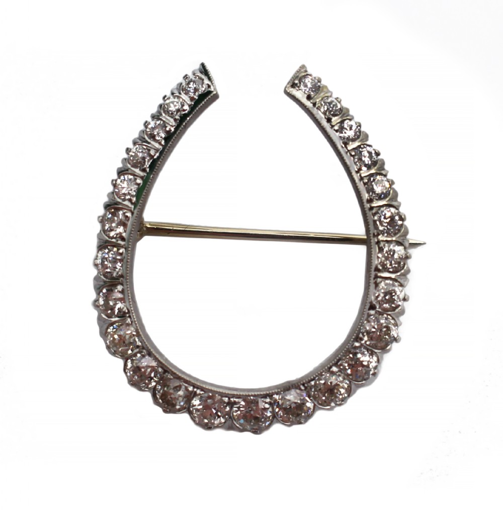 A platinum horseshoe-shaped brooch set with a graduating row of circular diamonds and fitted with a pin fastener on the reverse.