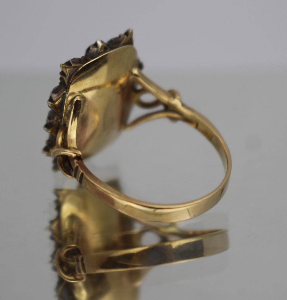 A Victorian gold mourning ring featuring a central rectangular compartment of woven hair surrounded by twelve purple glass stones. View III
