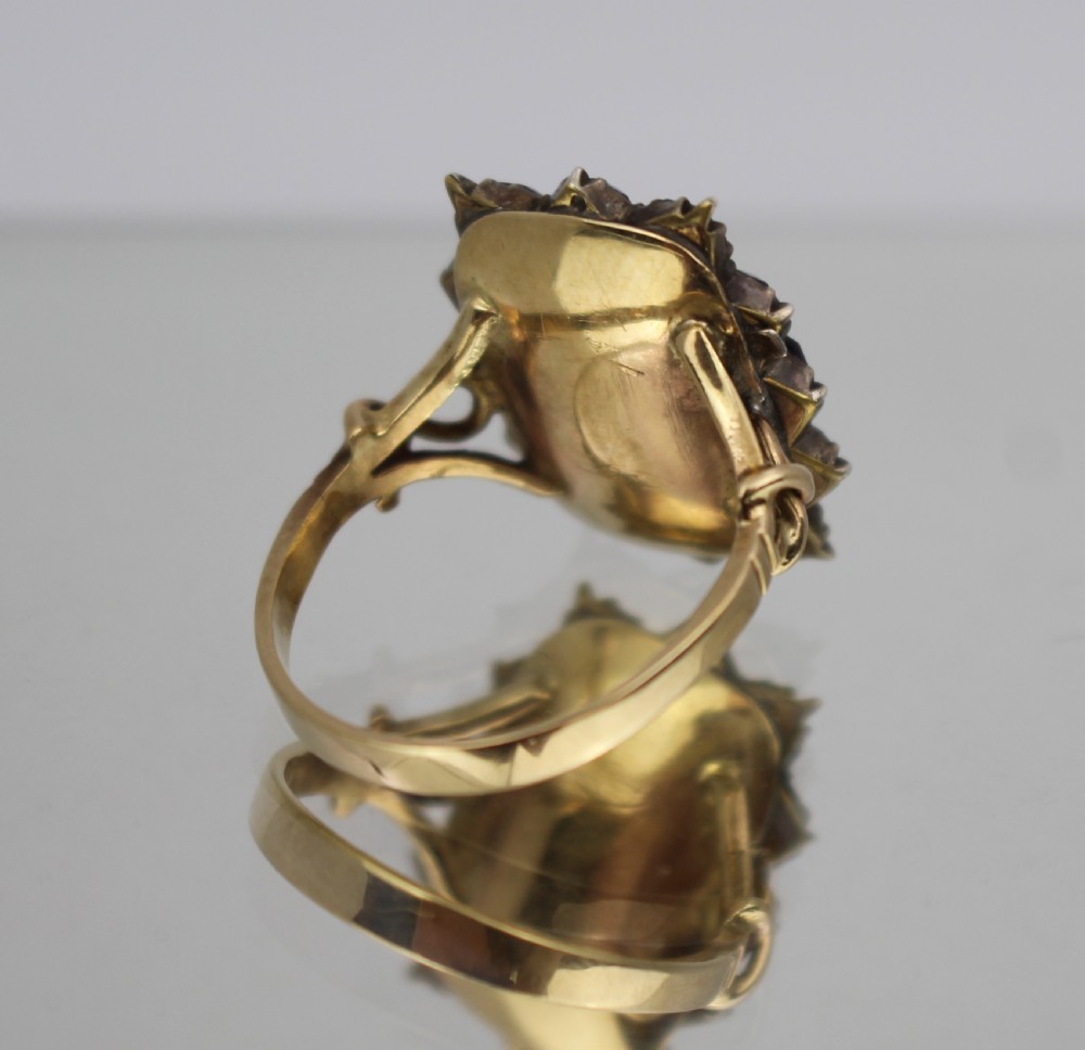 A Victorian gold mourning ring featuring a central rectangular compartment of woven hair surrounded by twelve purple glass stones. View IV
