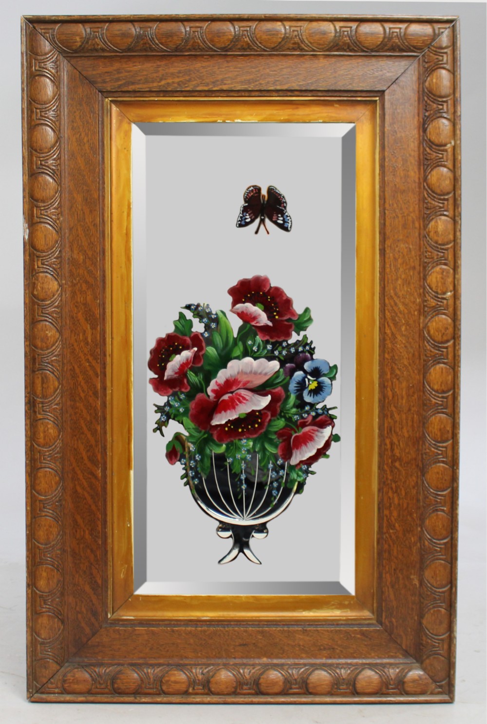 A rectangular Victorian mirror featuring hand-painted floral motifs and a butterfly on the glass, encased within a gilded slip and a carved oak frame.