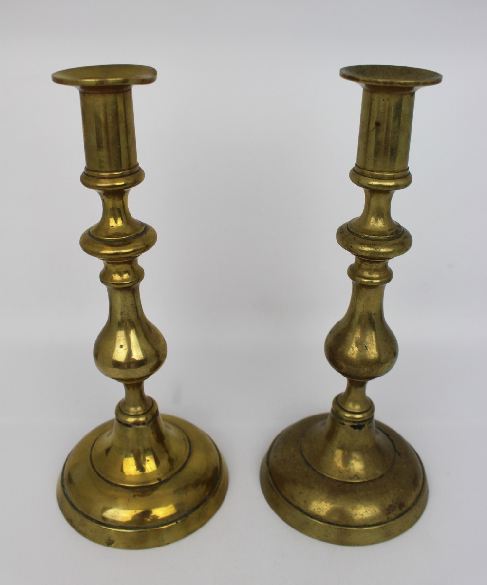 A pair of 19th-century brass candlesticks featuring turned baluster stems and rounded circular bases. View II