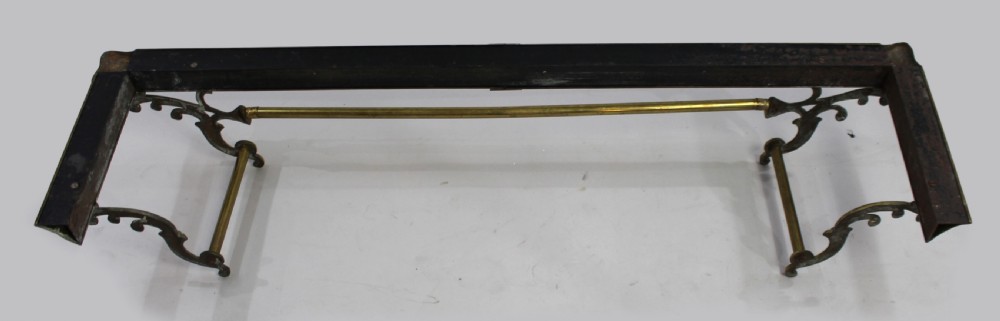 A Victorian brass fire fender with cast scroll end supports and a central horizontal rail resting on a low metal kerb. View IV