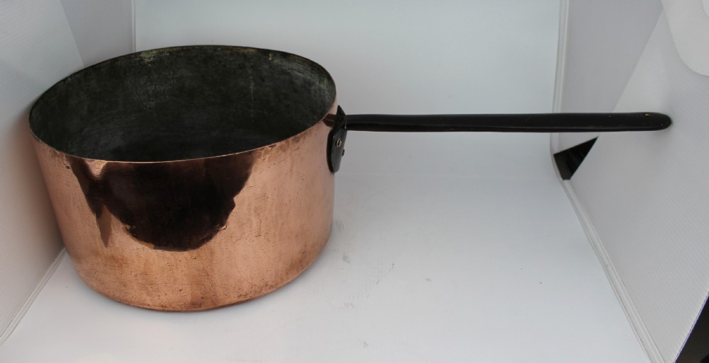 A large Georgian copper saucepan with a polished copper body, tin-lined interior, and a long black iron handle attached with rivets. View II