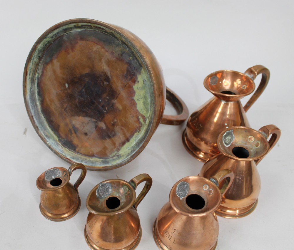 A set of six graduated antique copper haystack liquid measures ranging in size from one gallon down to one eighth gill, arranged on a plain background. View III