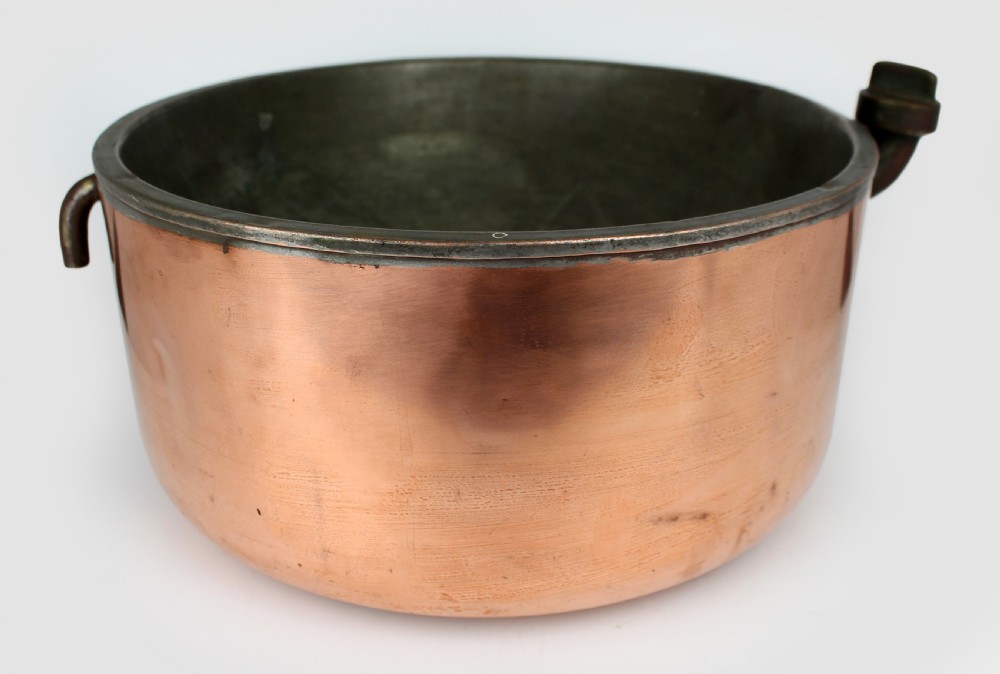A large round antique copper bain marie pan featuring a dark tin-lined interior and side handles.