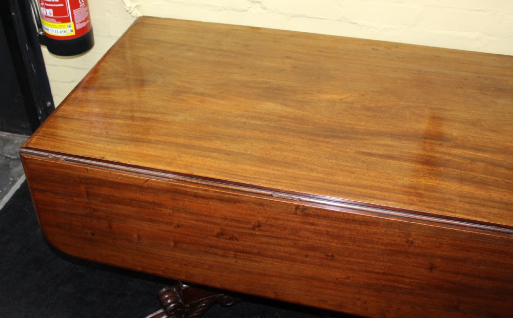 A polished mahogany William IV drop-leaf centre table featuring a rectangular top, drop sides, and a carved pedestal base with scroll feet. View III