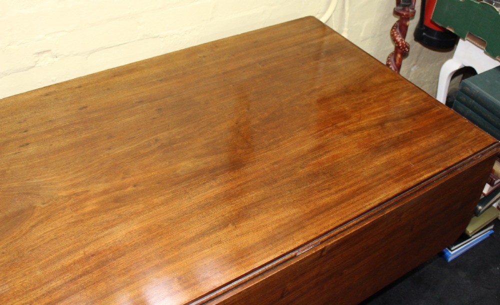 A polished mahogany William IV drop-leaf centre table featuring a rectangular top, drop sides, and a carved pedestal base with scroll feet. View IV