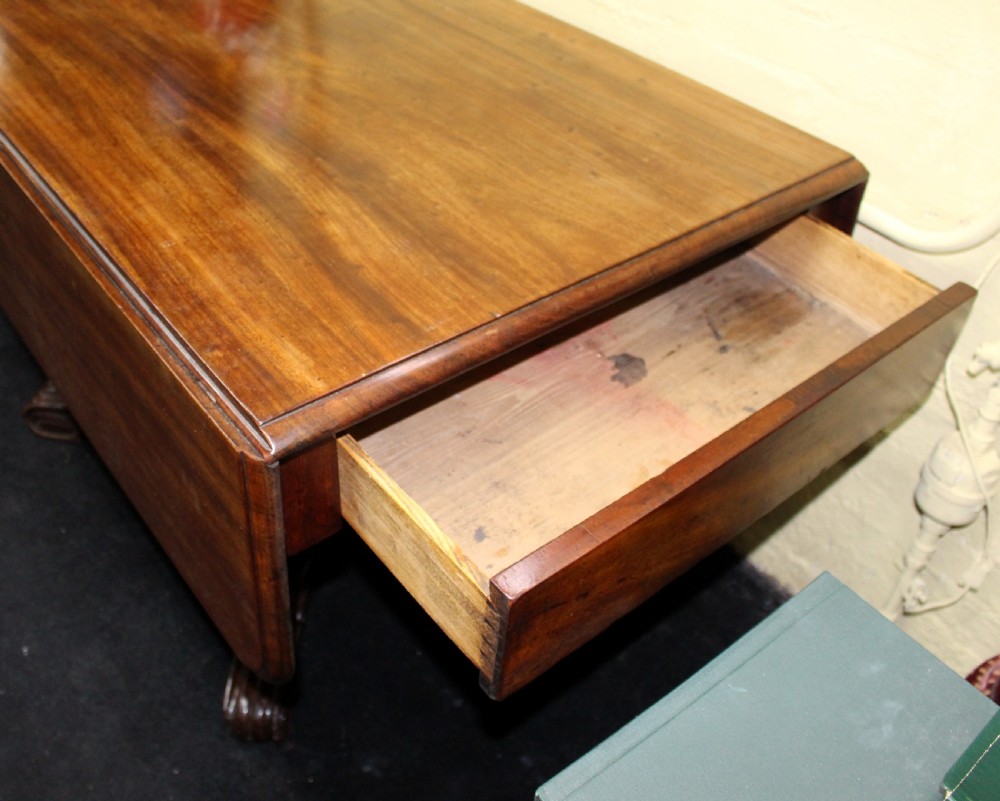 A polished mahogany William IV drop-leaf centre table featuring a rectangular top, drop sides, and a carved pedestal base with scroll feet. View V