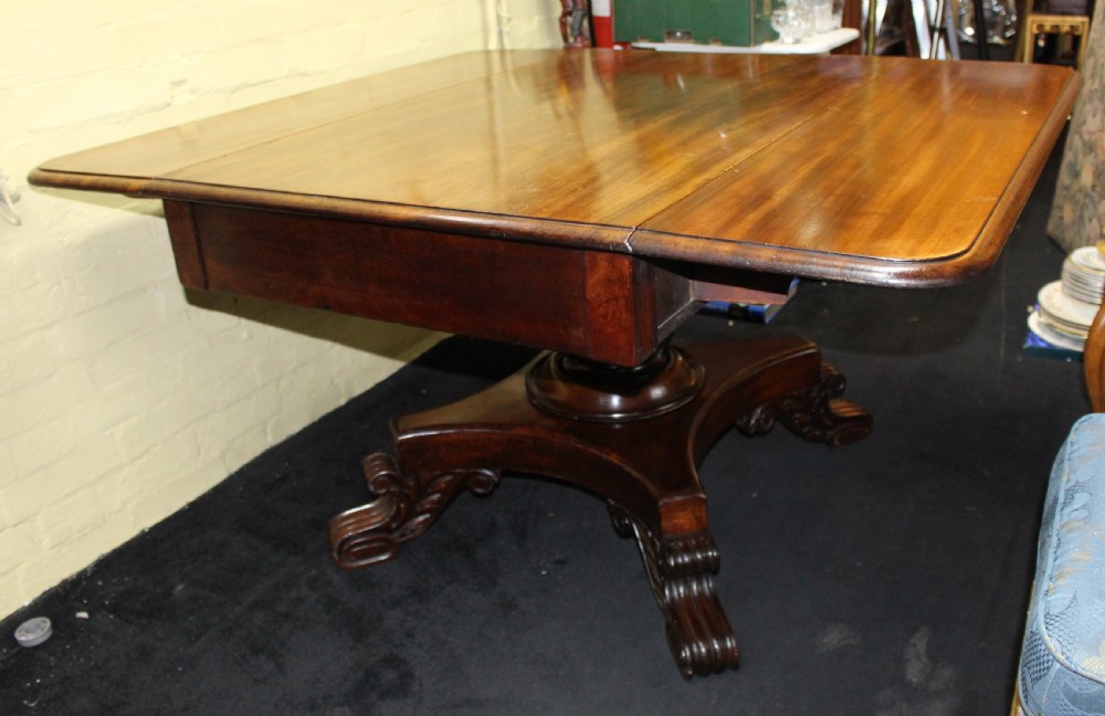 A polished mahogany William IV drop-leaf centre table featuring a rectangular top, drop sides, and a carved pedestal base with scroll feet. View VI
