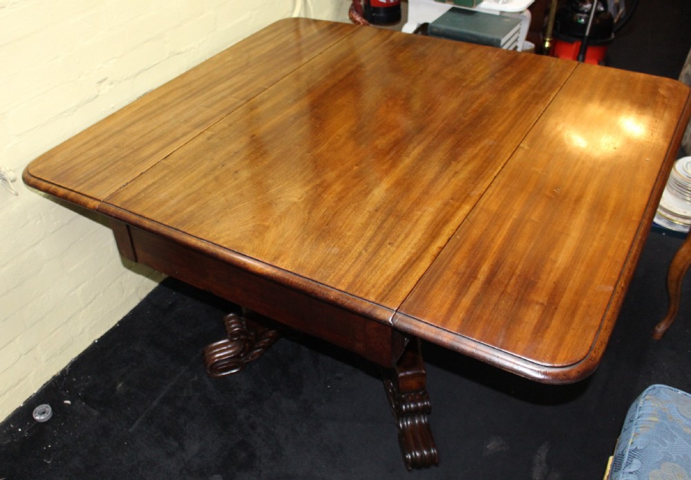A polished mahogany William IV drop-leaf centre table featuring a rectangular top, drop sides, and a carved pedestal base with scroll feet. View VII