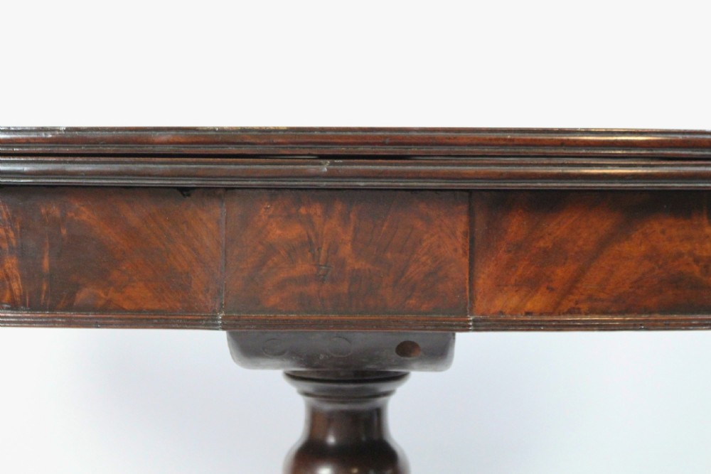 An early nineteenth-century Regency flame mahogany tea table featuring a fold-over top, turned central pedestal column, and four carved splayed legs with brass castors. View VII