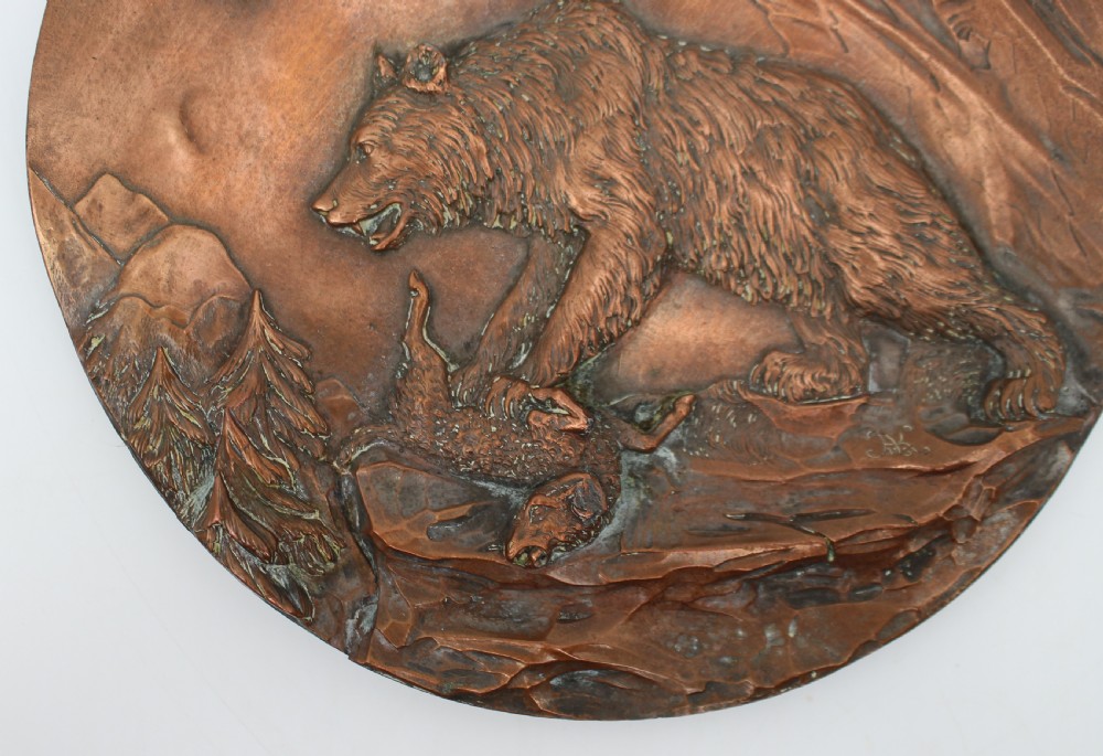 A circular antique copper relief plaque depicting a bear with prey in a rocky forest setting under an oak branch. View III