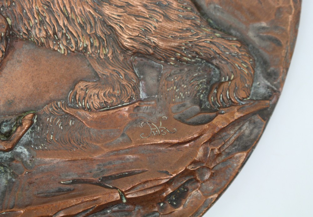 A circular antique copper relief plaque depicting a bear with prey in a rocky forest setting under an oak branch. View V