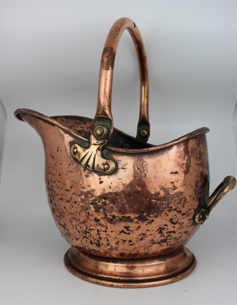 A Victorian helmet-shaped copper coal scuttle featuring an overhead swing handle, rear brass handle, and a round pedestal base. View III