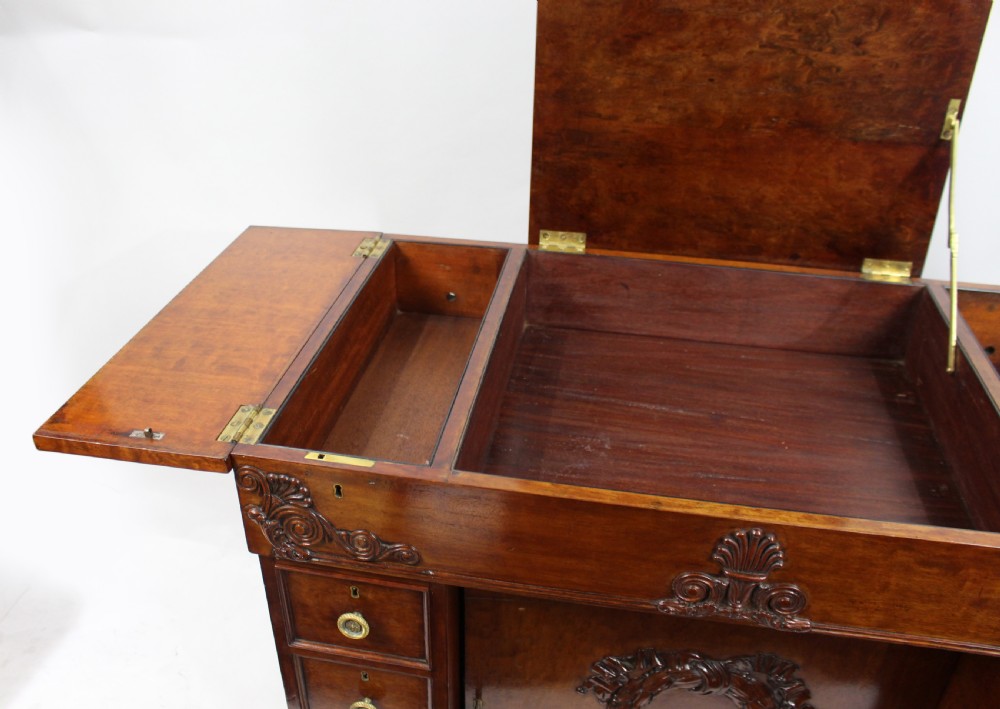Late 18th-century mahogany kneehole desk featuring carved lion paw feet, brass ring drawer handles, and a central cupboard door decorated with a carved laurel wreath. View VII
