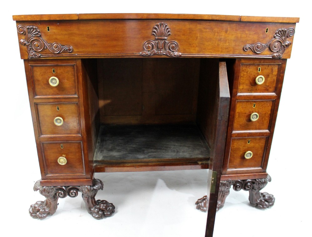 Late 18th-century mahogany kneehole desk featuring carved lion paw feet, brass ring drawer handles, and a central cupboard door decorated with a carved laurel wreath. View IX