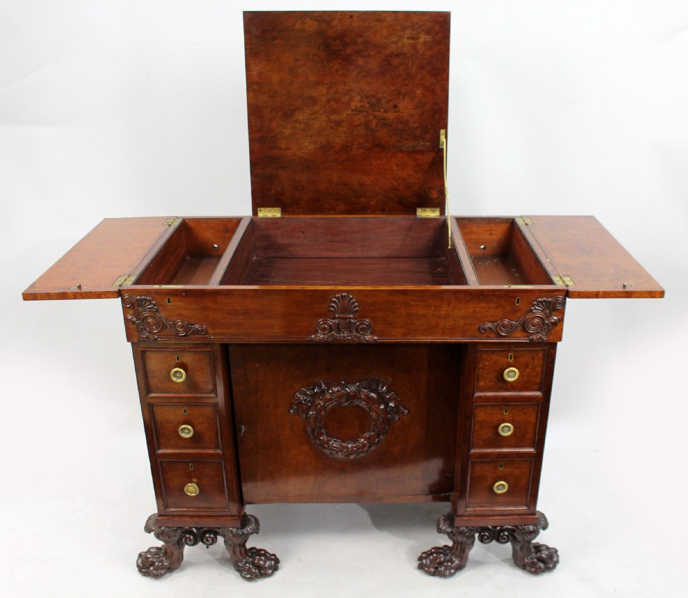 Late 18th-century mahogany kneehole desk featuring carved lion paw feet, brass ring drawer handles, and a central cupboard door decorated with a carved laurel wreath. View XI