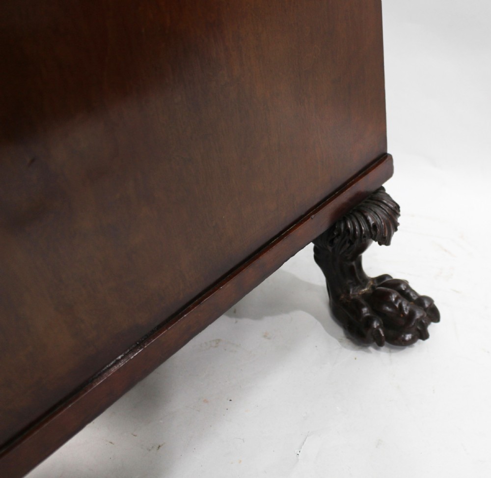 Late 18th-century mahogany kneehole desk featuring carved lion paw feet, brass ring drawer handles, and a central cupboard door decorated with a carved laurel wreath. View XIII