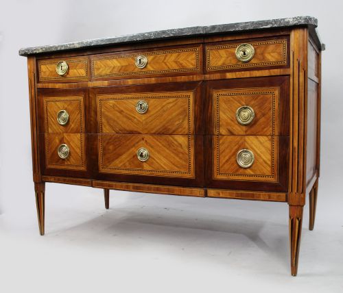 fig 2. A Louis XVI parquetry commode featuring geometric timber inlays, a grey marble top, brass ring handles, and tapered legs.