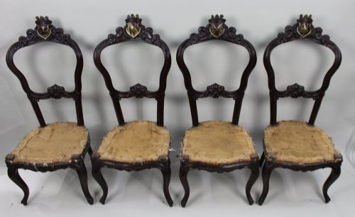 fig 1. A set of four mid-Victorian dark mahogany side chairs featuring open-carved balloon backs topped with heraldic crest shields and cabriole front legs.