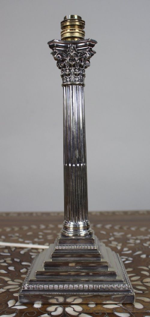 A silver-plated table lamp featuring a fluted Corinthian column shaft, a stepped square base, and a cream pleated fabric shade. View VI