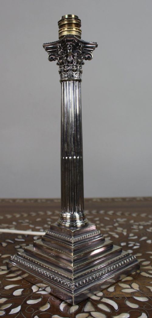 A silver-plated table lamp featuring a fluted Corinthian column shaft, a stepped square base, and a cream pleated fabric shade. View X