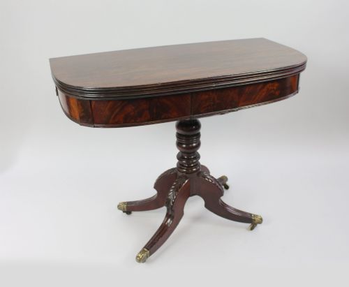 fig 1. An early nineteenth-century Regency mahogany tea table with a folded rounded top resting on a turned central column and four splayed legs with brass castors.
