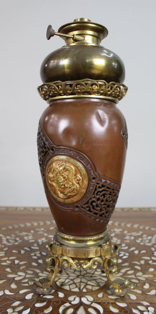 A Meiji period Japanese dark brown bronze oil lamp featuring reticulated openwork, a gilded dragon roundel, brass burner fittings, and decorative scroll feet. View IV