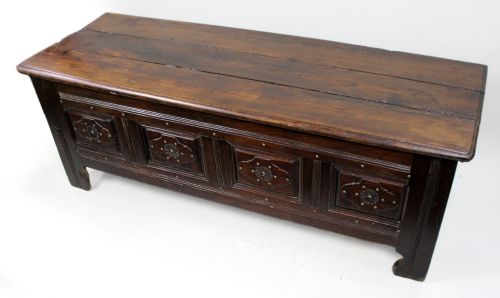 fig 1. A low rectangular dark oak coffer with a plank lid and four carved recessed panels accented with brass studs.