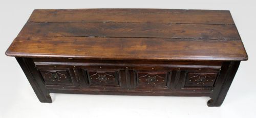 fig 2. A low rectangular dark oak coffer with a plank lid and four carved recessed panels accented with brass studs.
