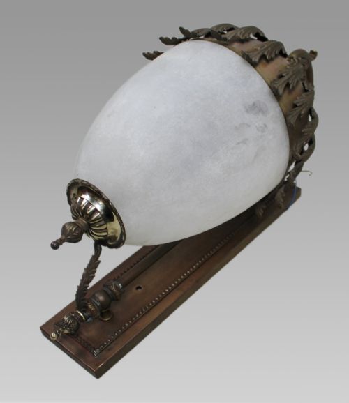 fig 1. An antique brass wall lantern featuring a frosted ovoid glass shade draped with cast acanthus leaves and topped with a decorative cresting collar.