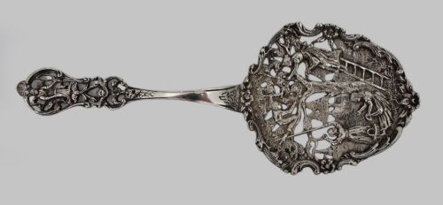 fig 1. An antique Flemish silver spoon featuring an intricately pierced bowl decorated with a figurative orchard scene and a scrolling openwork handle.