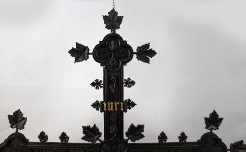 fig 1. A 19th-century dark carved wood cross adorned with detailed foliate motifs and a gilt INRI inscription at the upper section.