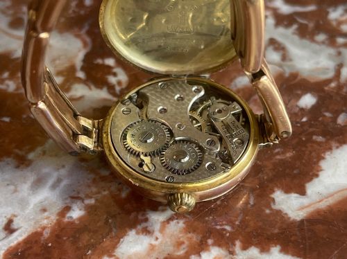 fig 2. An antique circular 9ct gold wristwatch with a cream enamel dial, Arabic numerals, red twelve, and an expanding gold link bracelet.