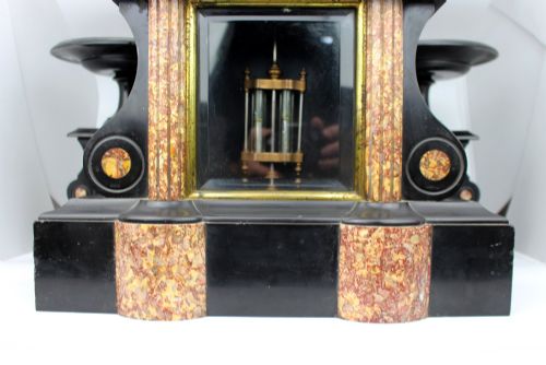 fig 3. A 19th-century French black slate and red variegated marble clock garniture set with a central architectural clock and flanking side tazzas.