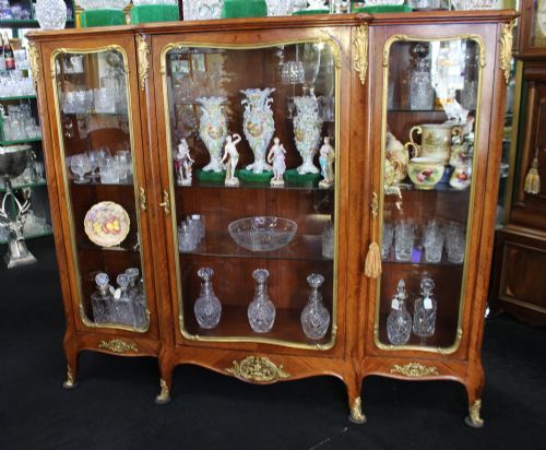 fig 1. A large French kingwood display cabinet featuring three glass doors, gilded bronze mounts, and cabriole legs.
