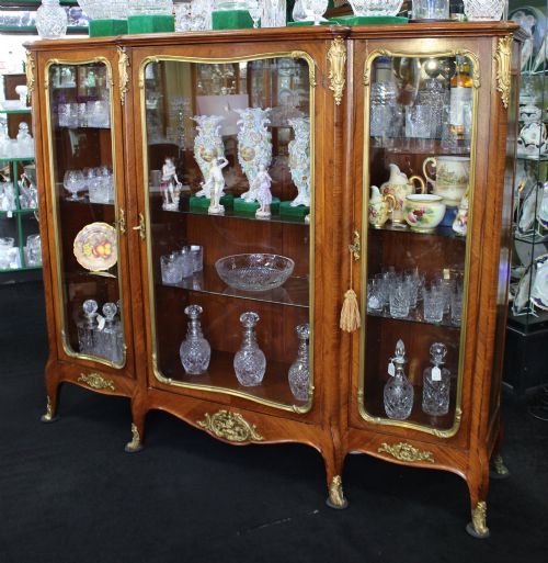 fig 2. A large French kingwood display cabinet featuring three glass doors, gilded bronze mounts, and cabriole legs.