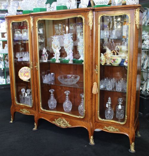fig 3. A large French kingwood display cabinet featuring three glass doors, gilded bronze mounts, and cabriole legs.